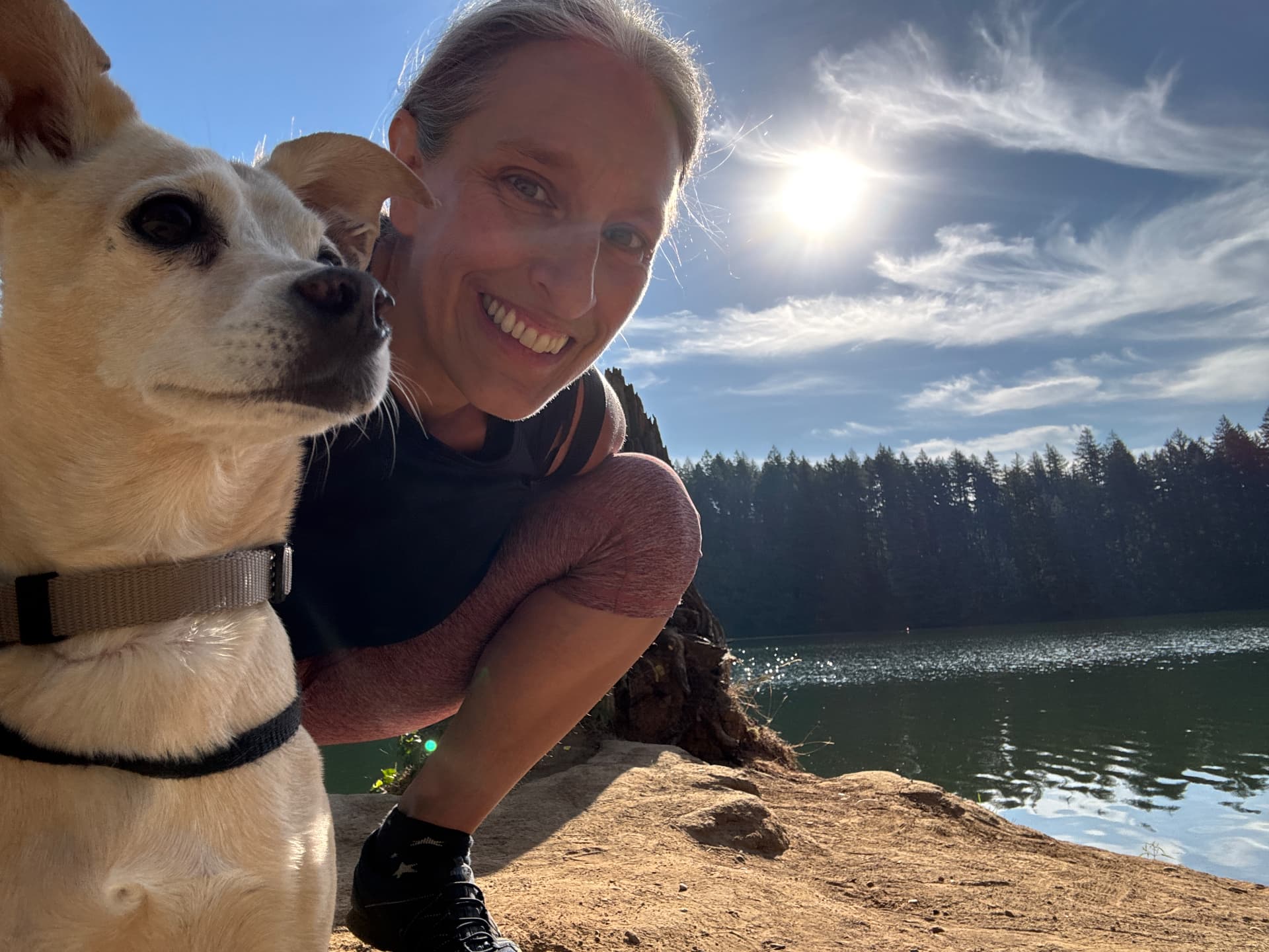 Connie leaning in cheek to cheek with Sami on a sunlit rock above Round Lake, Washington